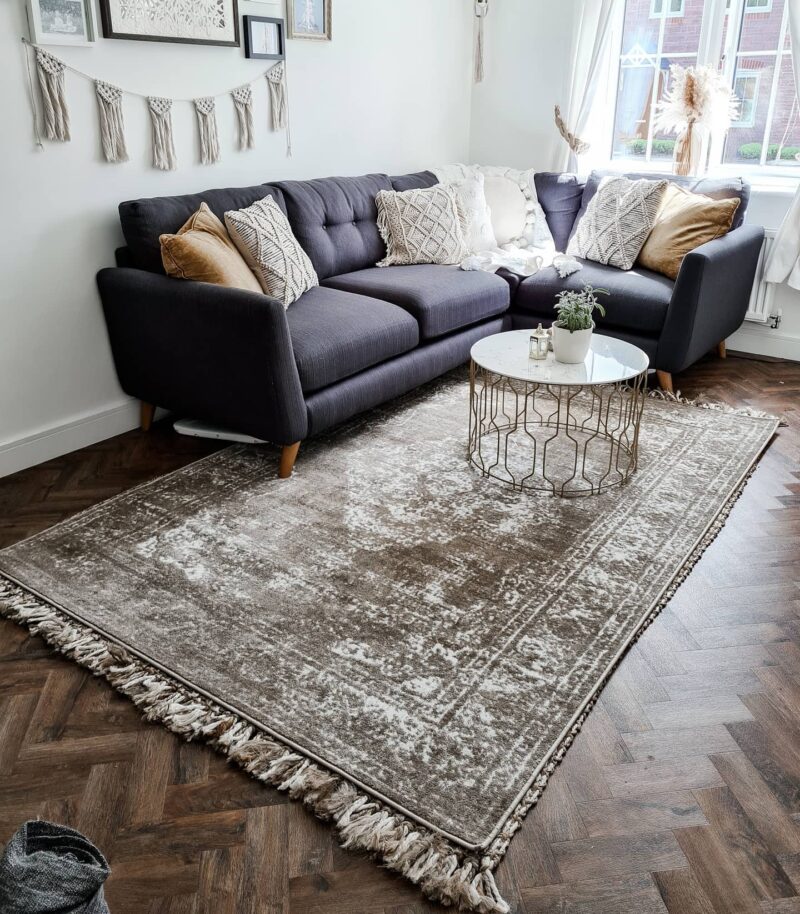 Dark blue Evie sofa with cream and beige cushions. Situated in a pale room with boho decor