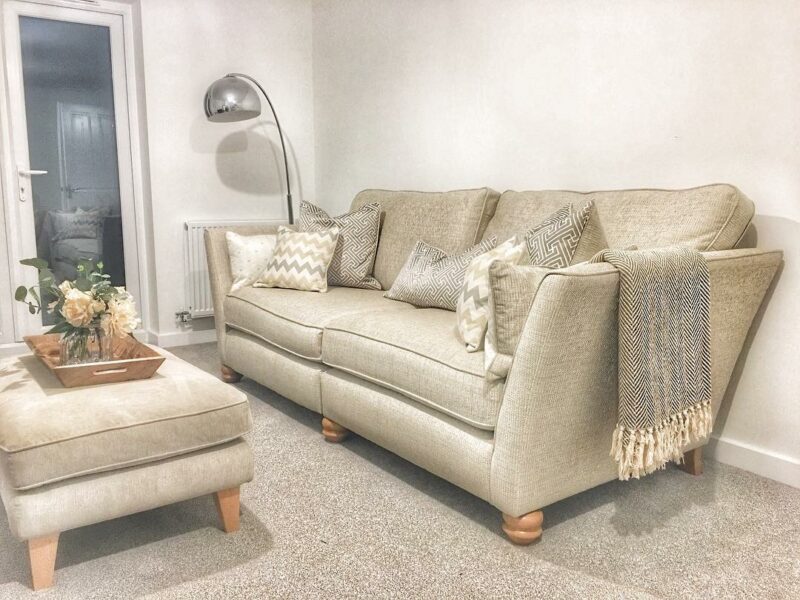 Beige sofa and footstool with grey cushions and throws