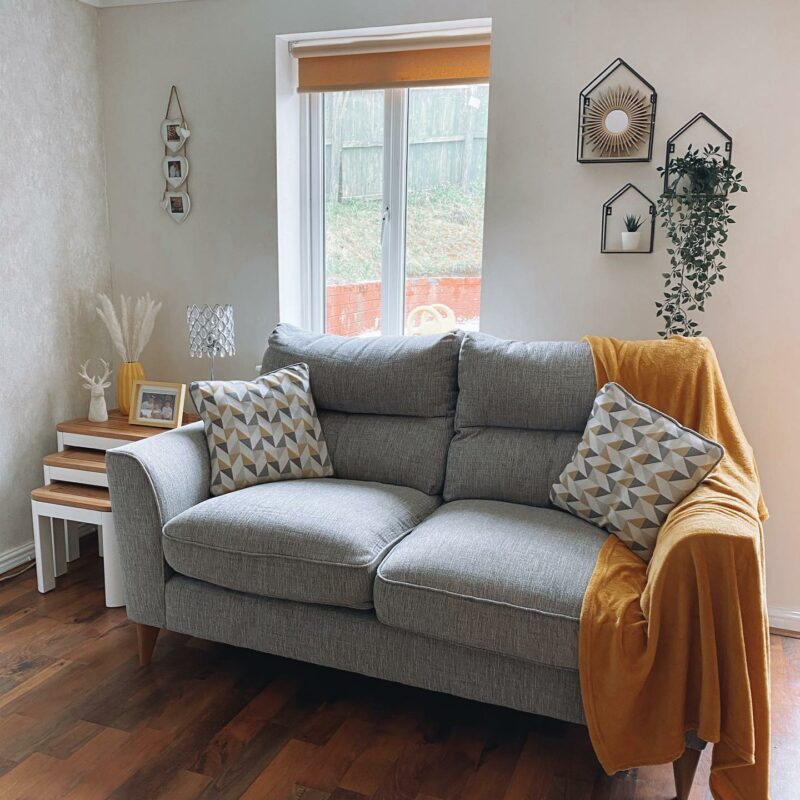 Grey sofa with yellow throw and patterned cushions