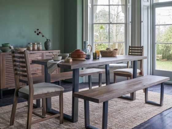 Detroit dark hardwood dining table with chairs and bench in light and airy dining room with green walls.