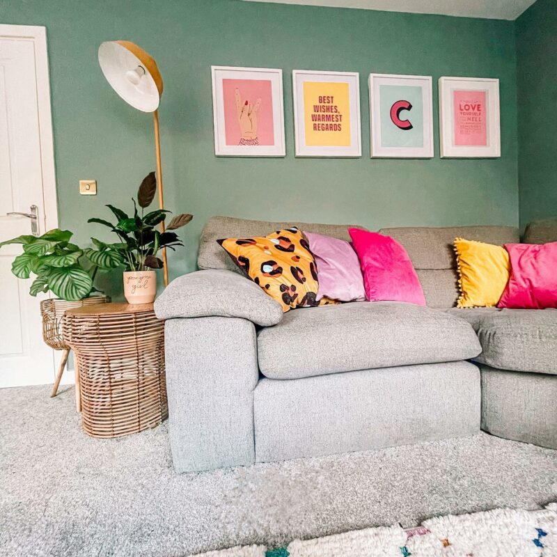 Grey Morgan sofa with brightly colour accent cushions. Pastel green wall with bright art.