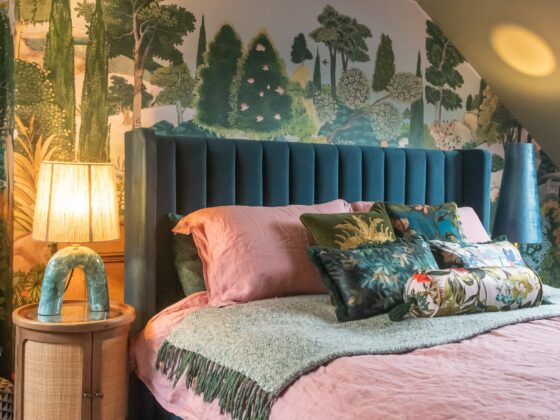A bed and bedside table-bedroom furniture-forest wall mural-teal upholstered bed-pink bedding-statement lamp-wooden bedside table-storage bed