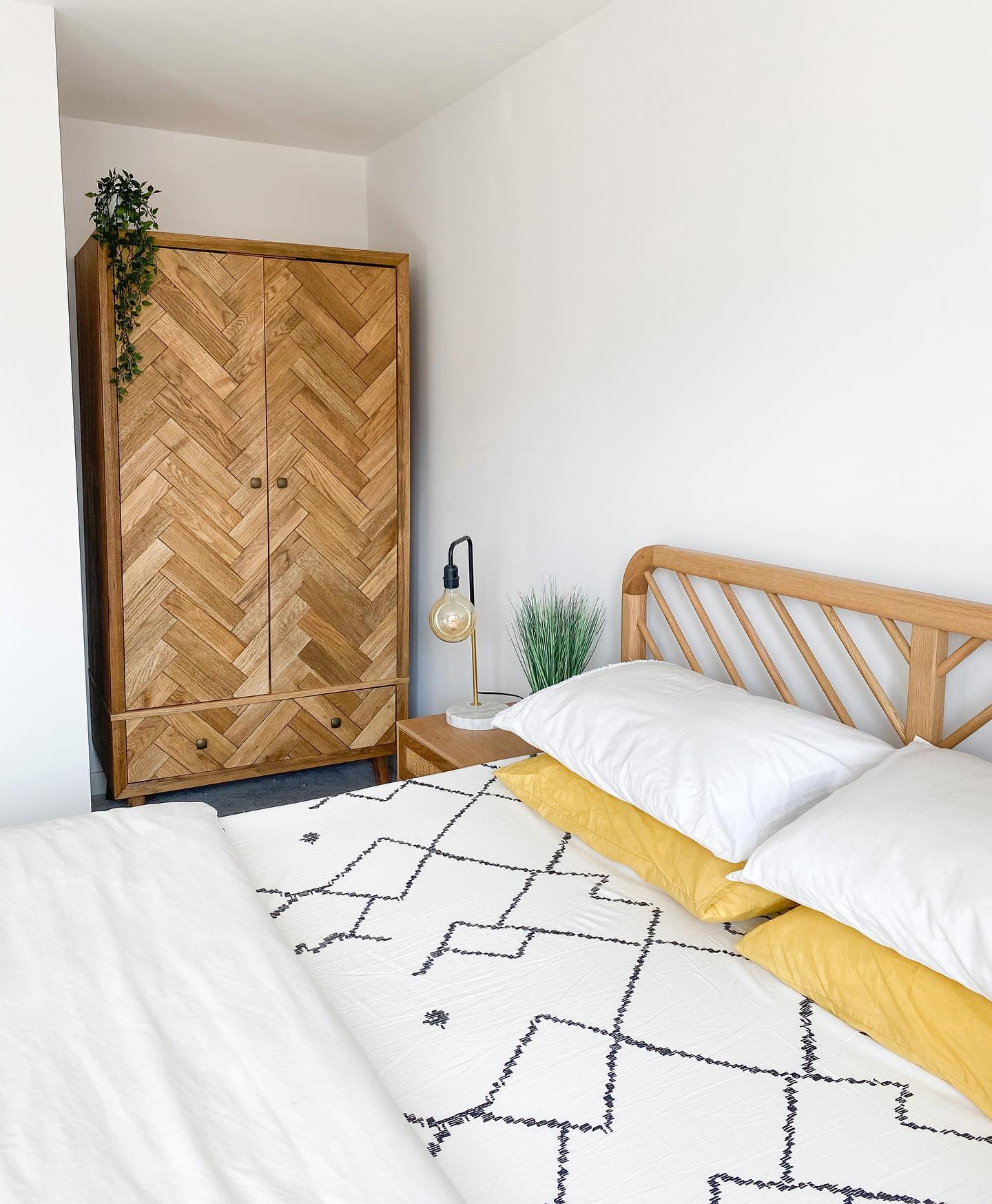 A bed, beside table and wardrobe-bedroom furniture-monochrome and yellow bedding-wooden bedside table-wooden triple wardrobe-wooden bed-bulb lamp
