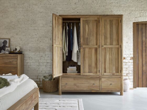 A wardrobe, bed, and chest of drawers-bedroom furniture-mango wood wardrobe-textured neutral rug-neutral painted brick wall-wooden door-polished concrete floor-green striped bedding