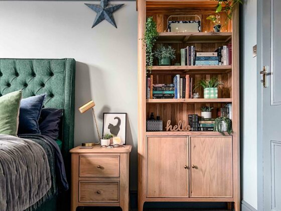 A bed, a bookcase and bedside table-bedroom furniture-upholstered double bed-wooden bedside table with drawers-wooden bookcase-green upholstered bed-grey wall colour