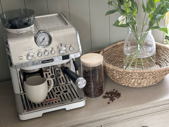 A sideboard-dining room furniture-coffee station-coffee machine-coffee beans in cannister-woven tray-fresh flowers in glass vase-weathered oak sideboard-neutral walls with panelling-striped blind