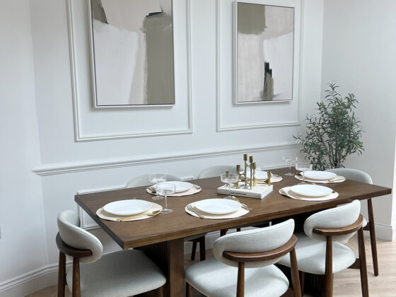 A dining table and chairs-dining room furniture-parquet floor-dark wood dining table-mid century style-dark wood and upholstered dining chairs-wall beading-neutral walls-abstract artwork-statement ceiling light-house plant-table place settings