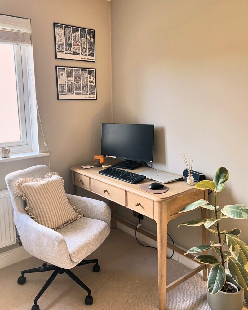 A desk and chair-home office furniture-oak desk with drawers-grey upholstered office chair-beige carpet-neutral walls-potted houseplant-white blinds-monochrome wall art-desktop computer-diffuser