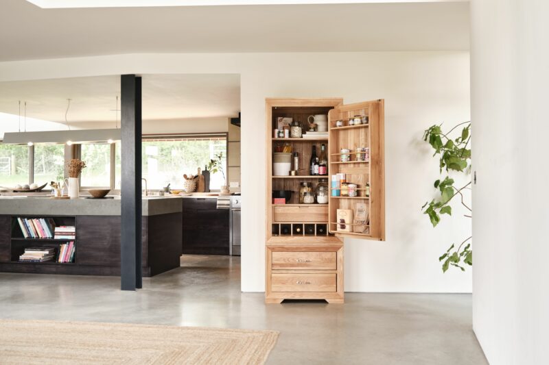 A larder-kitchen furniture-open plan living-wooden larder storing food and drink-house plant-industrial style-contemporary black kitchen-polished concrete floor-jute rug