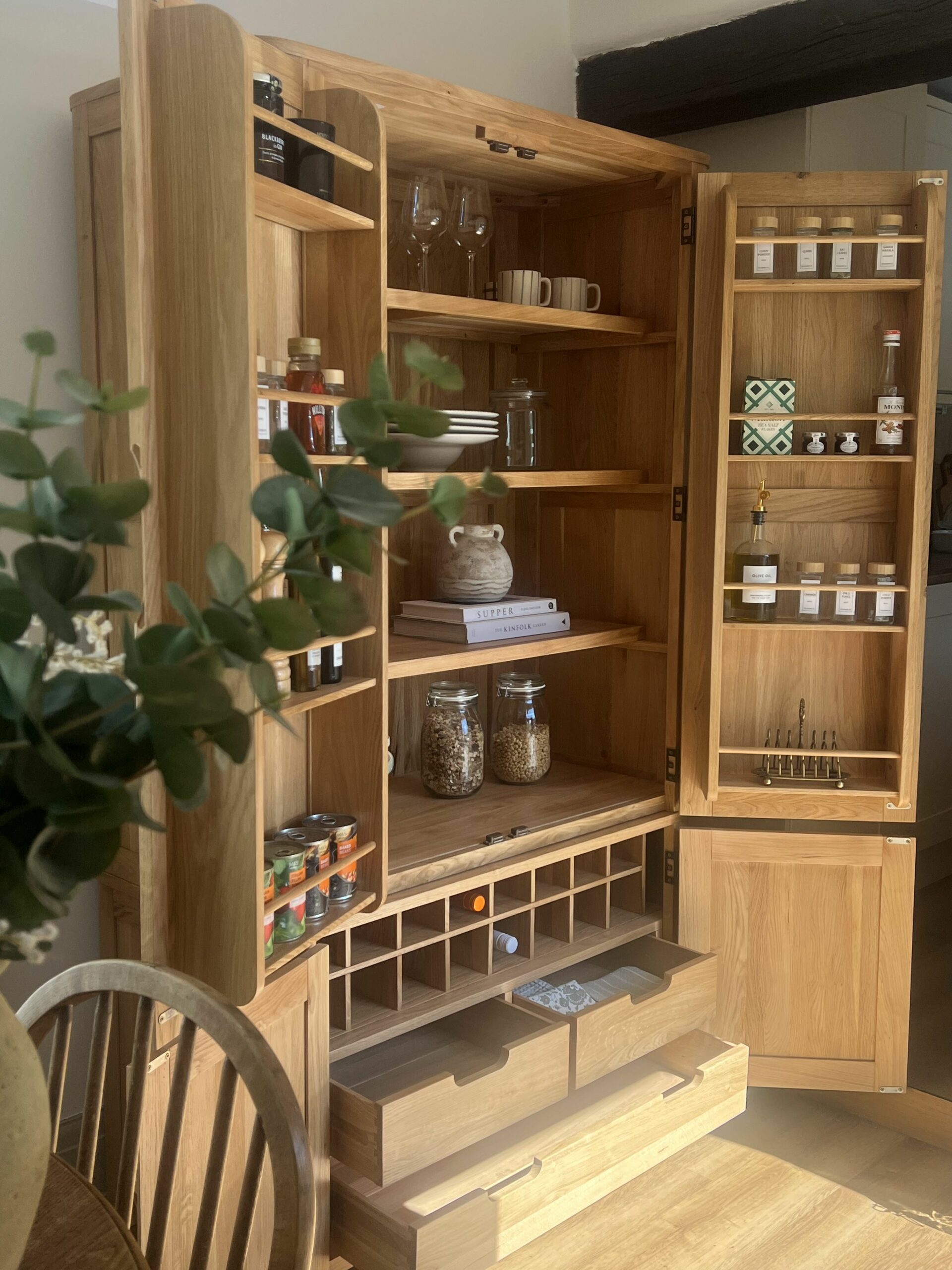A larder-kitchen diner furniture-open plan living-wooden larder storing food and drink-shelves with crockery-cook books-house plant-wooden chair