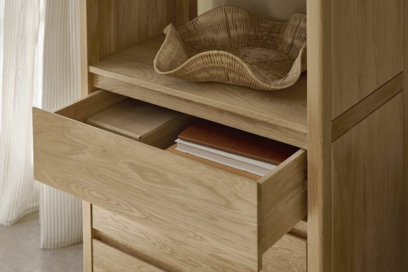 An open shelving unit-living room furniture-oak open shelving-wooden drawers-sculptural wicker tray-stacked books-sheer curtain-pale floow-natural light