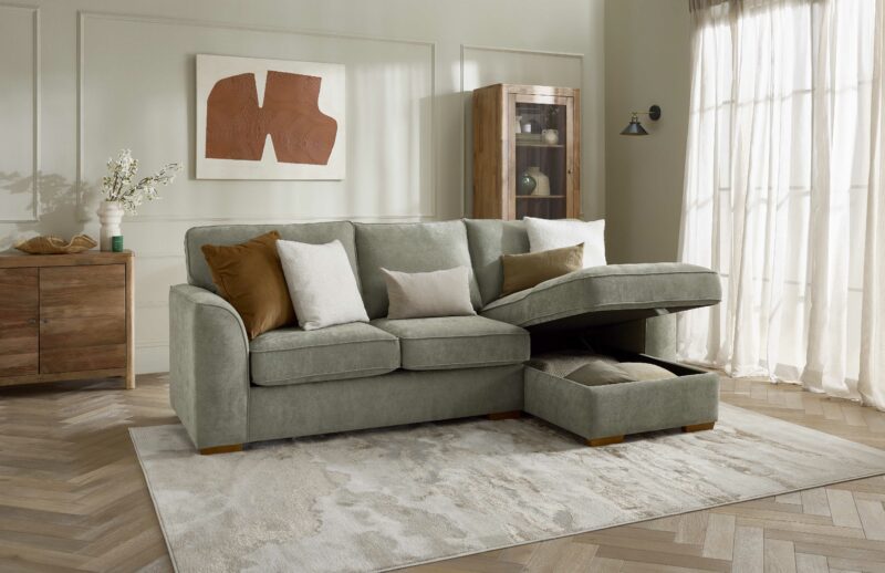 A sofa bed-living room furniture-green corner chaise sofa bed-beaded neutral walls-mango wood sideboard-display cabinet-abstract wall art-neutral rug-parquet floor-sheer curtain-block colour cushions