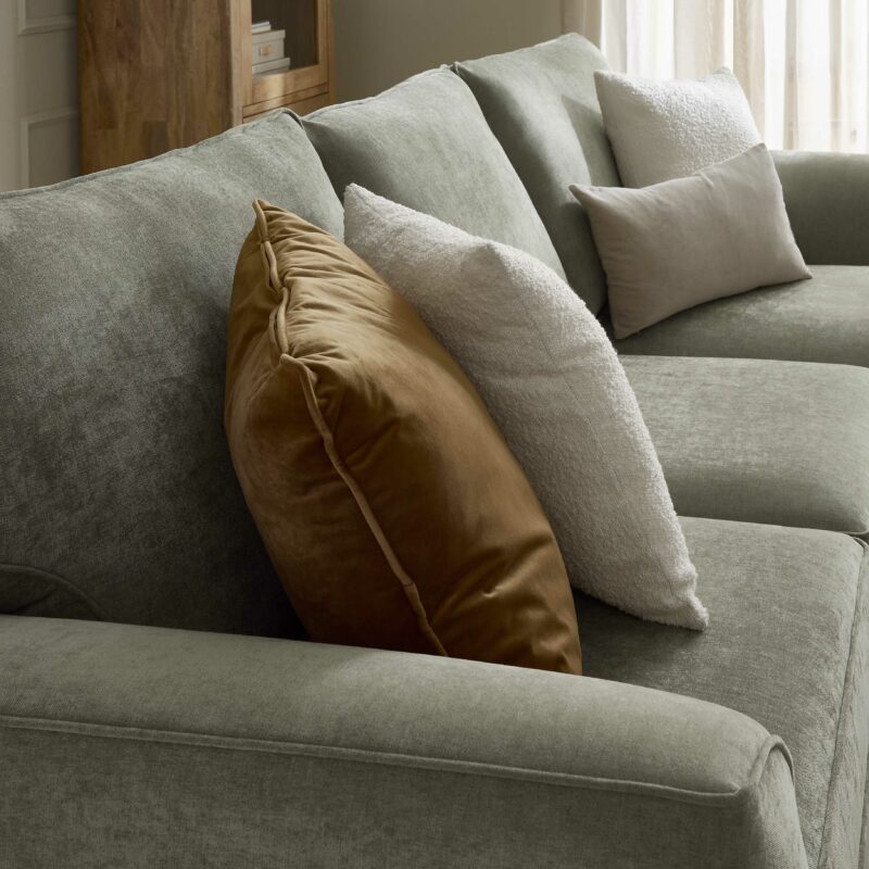 A sofa-living room furniture-a green chaise sofa-sheer curtain-wooden display cabinet-beaded walls-brown velvet cushion-boucle cushions-neutral cushions