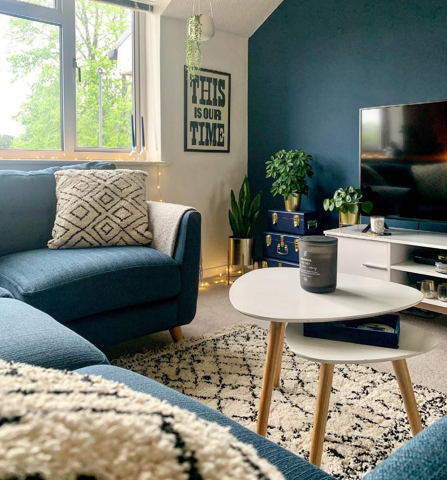 A corner sofa-living room furniture-blue L shaped sofa-textured rug-nest of tables-blue feature wall-TV unit