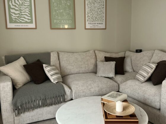 A modular corner sofa-living room furniture-beige corner sofa-monochrome accent cushions-marble and fluted wood coffee table-neutral walls-grey throw-green and white statement wall art