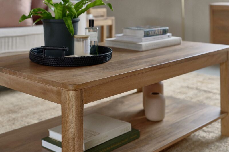 A coffee table-living room furniture-black rattan tray-house plant-candle-room spray-stack of books-vases-jute rug