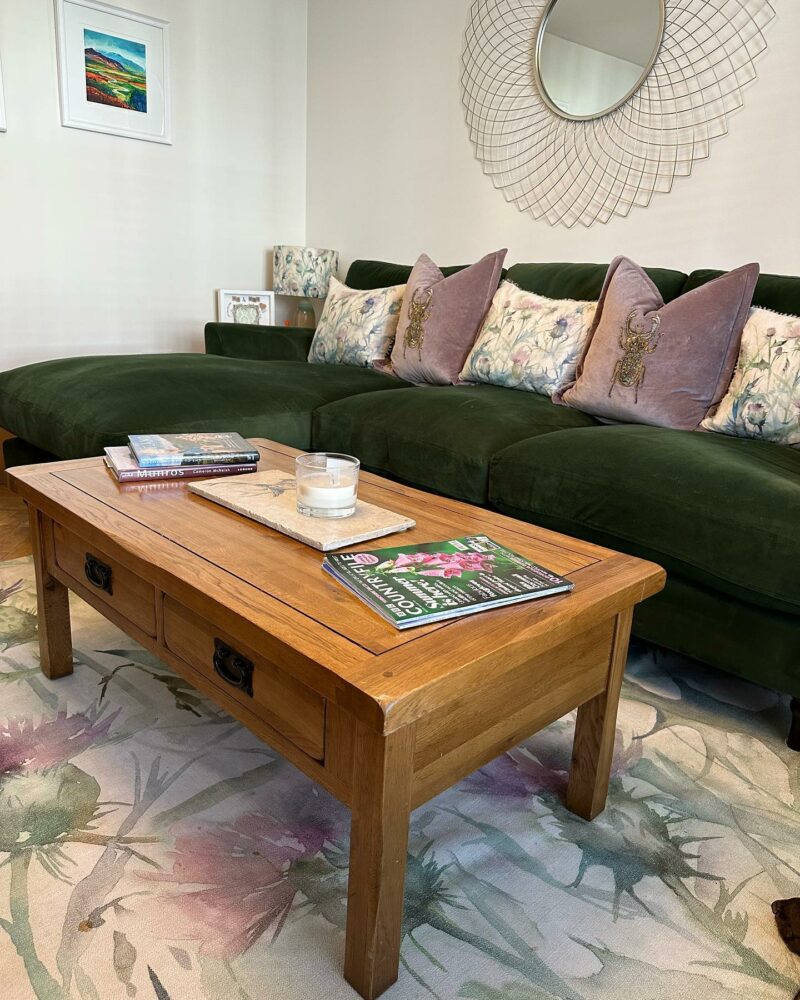 A coffee table and sofa-living room furniture-warm wooden coffee table with drawers-green velvet chaise corner sofa-patterned cushions-oversized ornate mirror-floral patterned rug