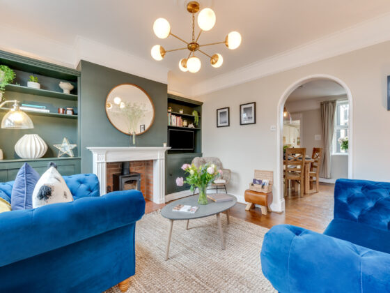 Oak Furnitureland blue velvet Montgomery sofa and armchair in living room with green walls.