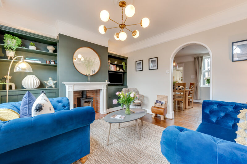Oak Furnitureland blue velvet Montgomery sofa and armchair in living room with green walls.