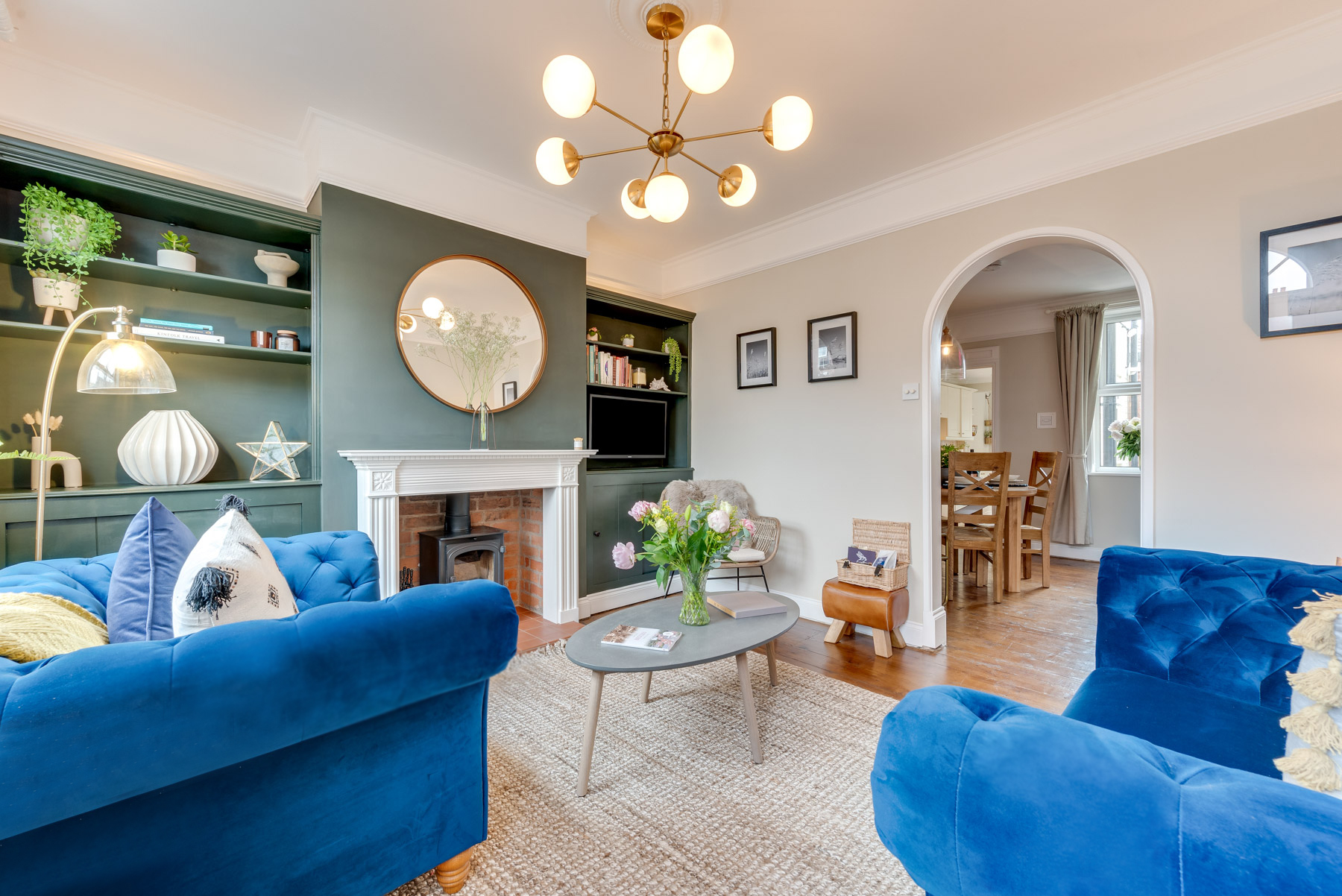 Oak Furnitureland blue velvet Montgomery sofa and armchair in living room with green walls.