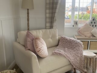 Cream Oak Furnitureland Evie loveseat styled with pale pink accessories.