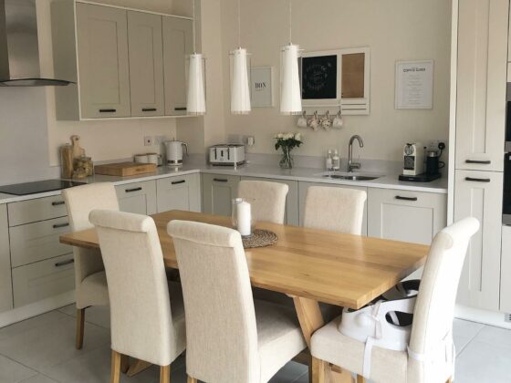 Neutral kitchen with Oak Furnitureland dining table and cream upholstered scroll back chairs.