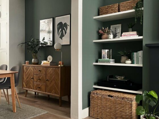 Living room/diner with walls painted in sage green and natural oak furniture.