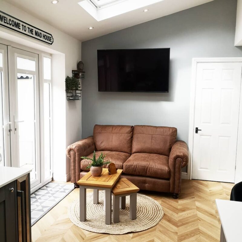 Kitchen seating nook with a brown sofa, nest of two tables and small plants.
